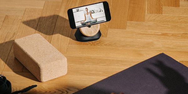 Wooden yoga blocks and a rolled mat on a floor.